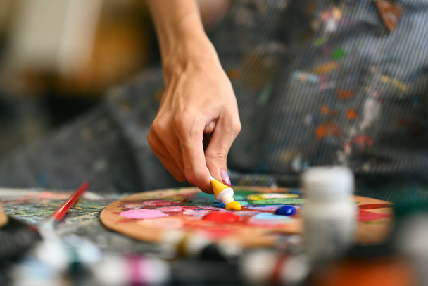 Vue rapprochée de l'artiste masculin mélangeant peinture à l'huile de couleur sur palette. Concept d'art, de passe-temps et d'activités de loisirs. - Photo, image