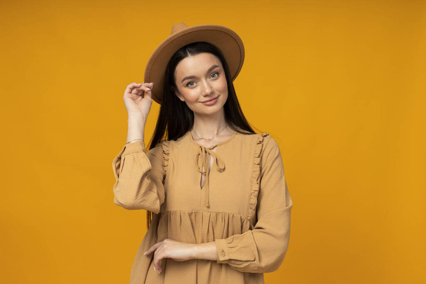 Young woman in a hat on a yellow background - Foto, Imagen