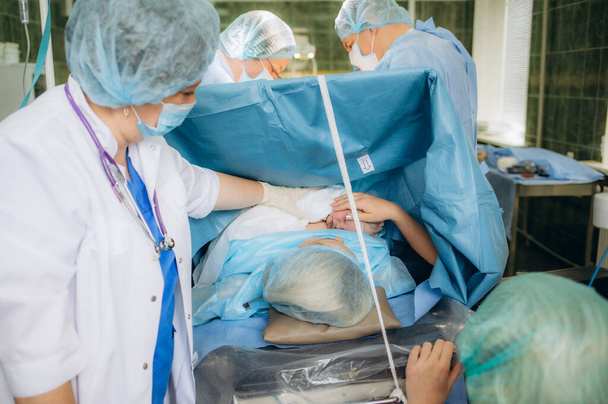 Sebészeti csapat teljesítő sebészet működését. Orvos műtét segítségével sterilizált eszközök. Orvosok és midwifes szülés. Csecsemő-szülészet. - Fotó, kép