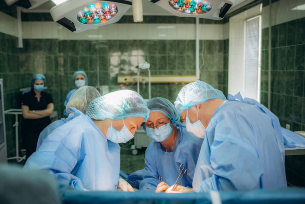a group of doctors sews up a woman after a caesarean section. - Photo, Image