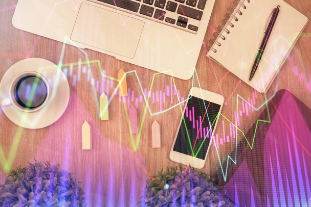 Double exposure of financial chart hologram over desktop with phone. Top view. Mobile trade platform concept. - 写真・画像