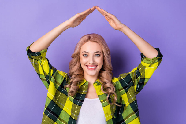 Photo of cheerful lovely girl toothy smile arms demonstrate make roof gesture above head isolated on violet color background. - Foto, afbeelding