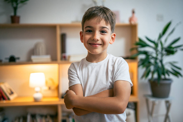 Un garçon enfant heureux caucasien préscolaire portrait stand à la maison espace de copie porter t-shirt blanc regardant vers l'appareil photo heureux confiant - Photo, image