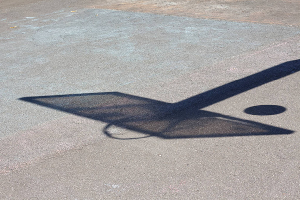 Egy kosárlabda háttámla árnyéka egy udvari sportpályán. - Fotó, kép