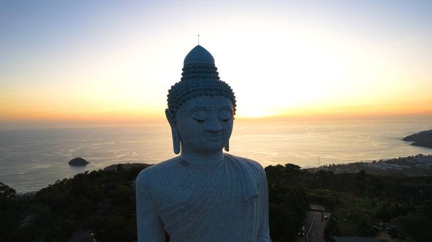 Gran Buda al atardecer vista desde un dron. Phuket. La gente sube las escaleras a la estatua. Las verdes colinas de la isla están alrededor. A lo lejos, el sol brilla sobre el mar. Vista desde arriba - Foto, Imagen