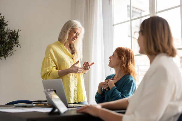 Three cheerful businesswomen in an office. Diverse group of businesswomen smiling while discussing. Successful female colleagues collaborating on a new project. - Foto, Imagen