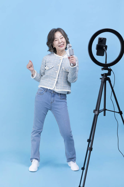 singing active young senior Korean Asian woman with smartphone, mobile karaoke concept - Φωτογραφία, εικόνα