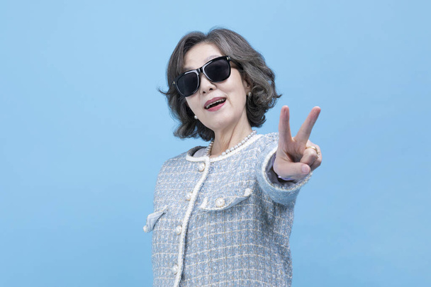 active young senior Korean Asian woman wearing sunglasses with hand motion - Фото, зображення
