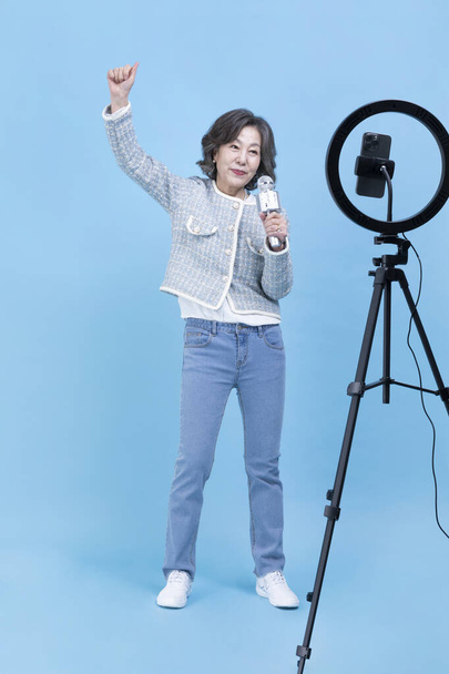 singing active young senior Korean Asian woman with smartphone, mobile karaoke concept - Zdjęcie, obraz