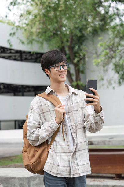 Estudiante masculino sostiene el teléfono móvil para tomar fotos en el campus. - Foto, imagen