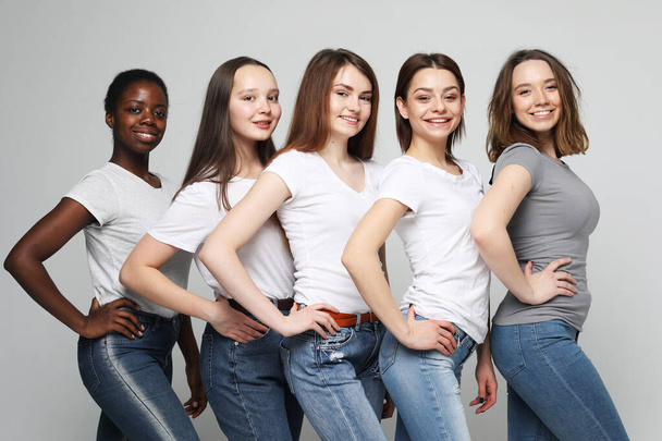 Group of happy young women of different size and ethnicity in t-shirts over light grey background - Foto, Imagen