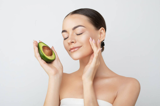 Beauty portrait of young topless woman showing halved avocado standing isolated over white background - Valokuva, kuva