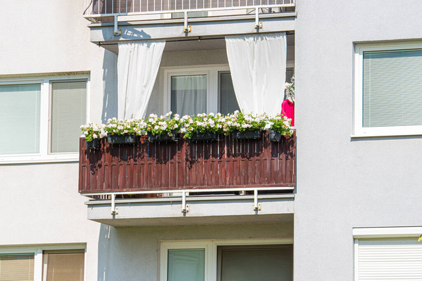 Balkon zieleni kwiatami w domu wielorodzinnym. - Zdjęcie, obraz