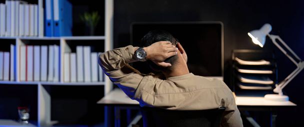 Überlastete junge asiatische Büroangestellte, die nachts Überstunden am Laptop macht. - Foto, Bild