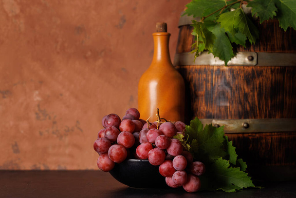 Wijn fles en weelderige druiven, presentatie van de artisticiteit van de wijnbereiding. met kopieerruimte - Foto, afbeelding