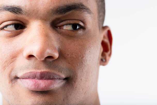 Großaufnahme Porträt eines jungen, lächelnden schwarzen Mannes, der geschickt seitwärts in Richtung Kopierraum blickt. Seine Augen suggerieren Interesse oder Zustimmung. Positiv - Foto, Bild