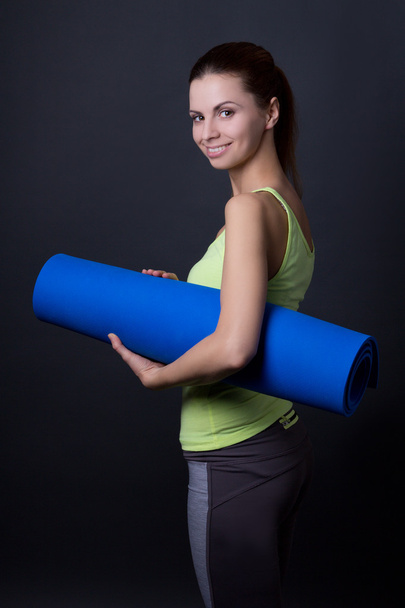 young woman in sports wear posing with yoga mat over grey - Valokuva, kuva
