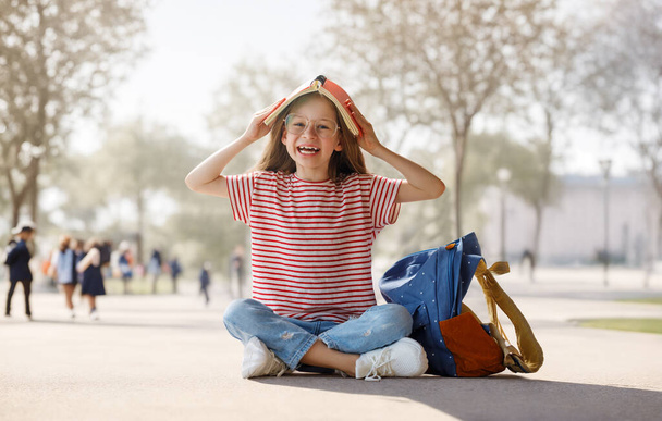 Pupil of primary school. Girl with backpacks outdoors. Beginning of lessons. First day of fall.     - Foto, imagen