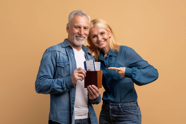 Tourism tourists traveler journey rest weekend vacation holiday relax concept. Photo portrait of excited elderly man and woman friends couple showing document with tickets isolated beige background - Photo, image