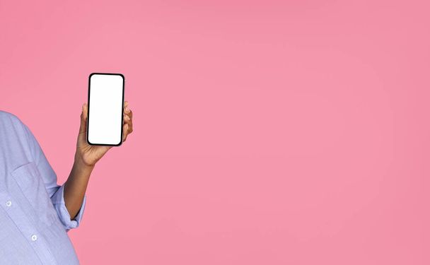 Millénaire afro-américaine enceinte avec ventre montrer smartphone avec écran vide, isolé sur fond de studio rose. App pour attendre bébé, blog, site Web, chat et réseaux sociaux - Photo, image