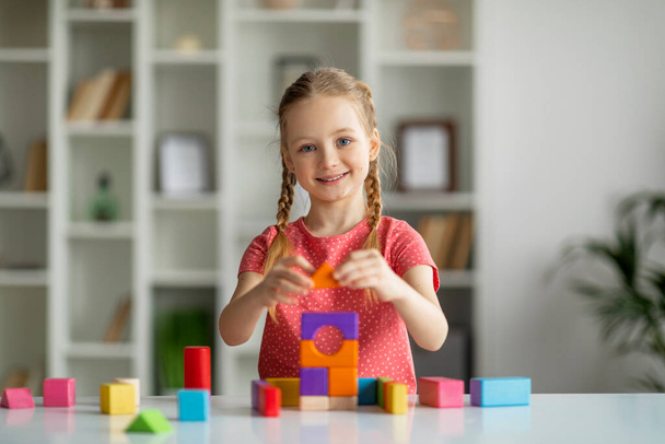 Działania rozwojowe. Cute Happy Little Girl Grając z kolorowych drewnianych cegieł w pomieszczeniach, Happy Kobieta budynku piramidy jasne bloki, Wesoły dzieciak korzystających z gier stołowych, Kopiuj przestrzeń - Zdjęcie, obraz