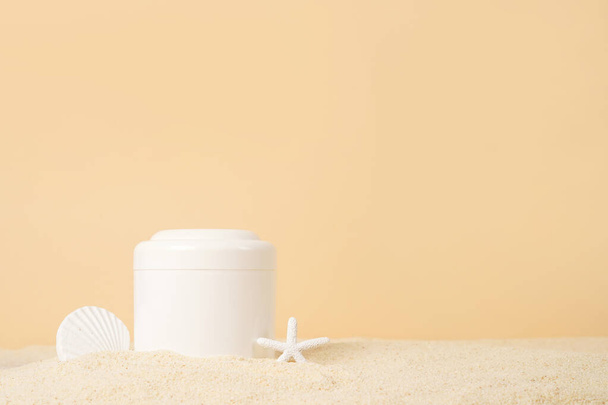 黄色の背景に砂の上にヒトデと白いボトルの化粧品クリーム、コピースペース。UVAとUVB保護。夏化粧品 - 写真・画像
