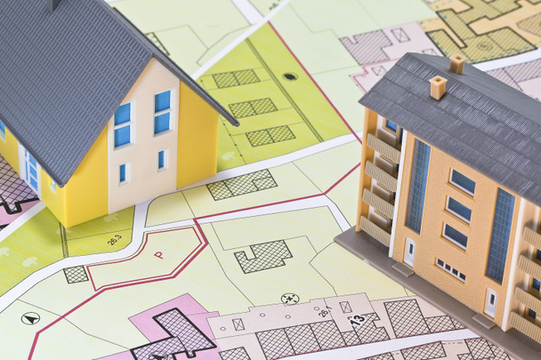 Eigentumswohnung versus Einfamilienhaus - Konzept mit Einfamilienhaus, Mehrfamilienhaus, imaginärem Katasterplan und allgemeiner Stadtplanung  - Foto, Bild