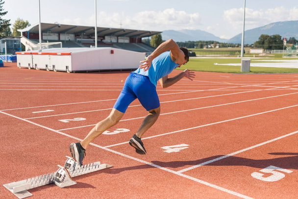 Young man training for run race start on a stadium track outside - 写真・画像