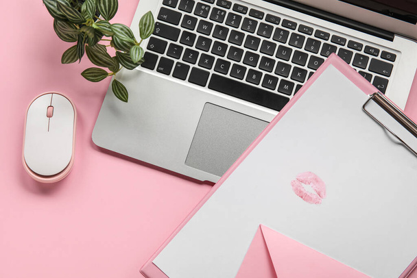 Буфер обмена с помадой знак поцелуя, конверт и ноутбук на розовом фоне - Фото, изображение