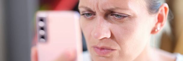 Close-up portret van de vrouw die kijkt naar smartphone display nauw met oogproblemen. Verziendheid myopie astigmatisme - Foto, afbeelding