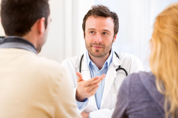 Young attractive doctor advising a young couple of patients - Foto, Bild