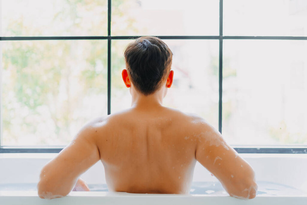 Back of asian man showering in the bathtub in the bathroom. - Фото, зображення