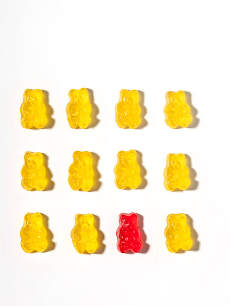 One red gummy bear among yellow gummy bears. Creative concept. - Fotoğraf, Görsel