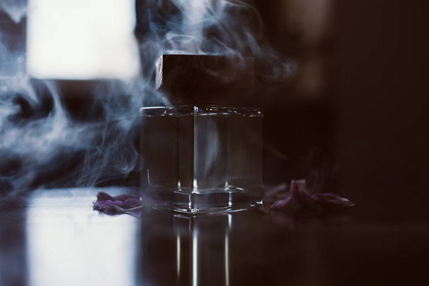 煙の中でスタイリッシュな香水のボトル - 写真・画像