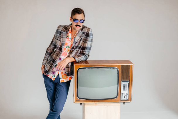Back in time 90s 80s lifestyle concept. Studio footage of stylish cheerful young man in vintage retro jacket with antique old tv, candy-colored fashions, creativity, emotions, facial expression - Foto, Imagem