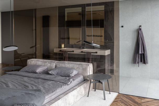 cool expensive interior design of room in prestigious luxury hotel with dark tones with modern LED lighting and stylish furniture. the area with a sink is separated by dark glass from the bedroom - Zdjęcie, obraz