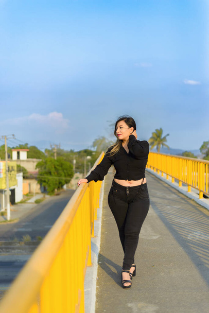 Портрет молодой женщины с позитивным настроем на пешеходном мосту. Закат с голубым небом. - Фото, изображение