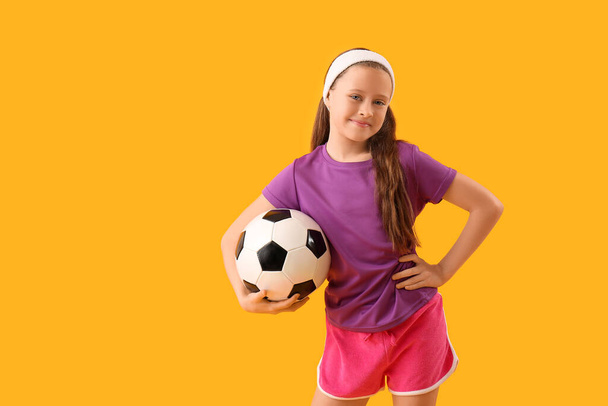 Ragazzina sportiva con pallone da calcio su sfondo giallo - Foto, immagini