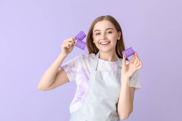 Female hairdresser with curlers on lilac background - Photo, Image