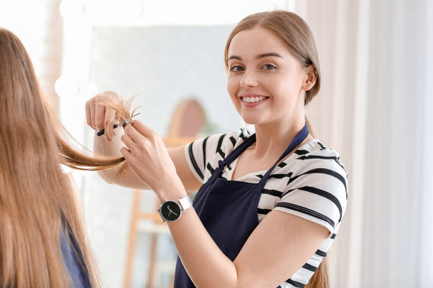 Жіночий перукар, що ріже волосся молодої жінки в салоні краси
 - Фото, зображення