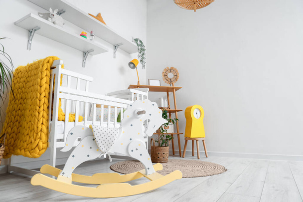 Стильный интерьер детской комнаты с детской кроватью и качающейся лошадью - Фото, изображение