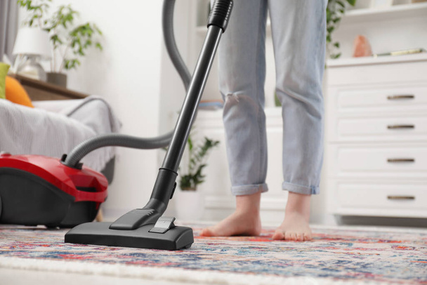 Woman cleaning carpet with vacuum cleaner at home, closeup - Valokuva, kuva