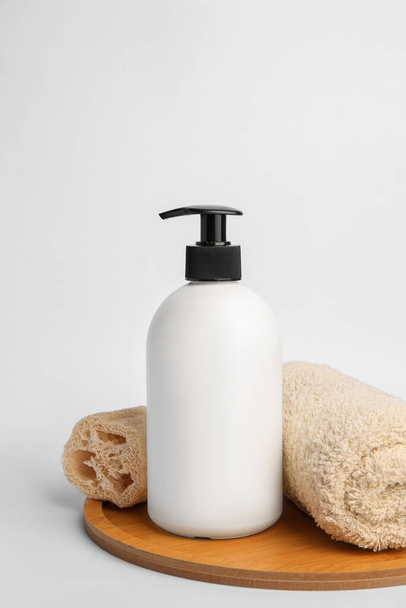 Bottle with cosmetic product, rolled towel and loofah sponge on white background - Φωτογραφία, εικόνα