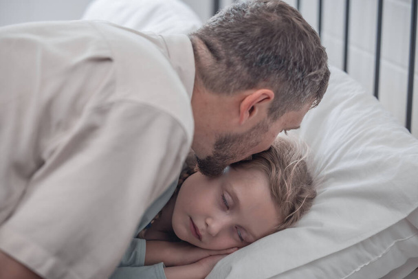 Father singing his daughter to sleep, providing comfort, support, and security. Focusing on fulfilling both physical and emotional needs. Kids sometimes act happy while pretending to fall asleep. - Foto, imagen