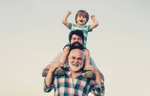 Excited. Father and son playing outdoors. Happy smiling boy on shoulder dad looking at camera. Happy family. Three men generation - Φωτογραφία, εικόνα
