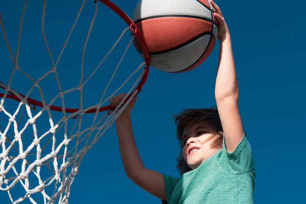 Excited funny kid playing basketball. Closeup child portrait. Funny child face. Little basketball player making slam dunk - Foto, imagen