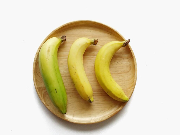 Three banana fruits on wood dish with white background. - Fotoğraf, Görsel