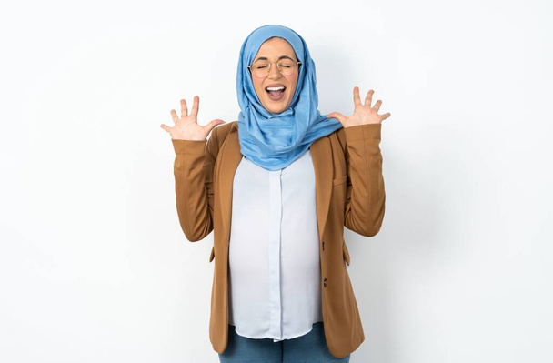 Emotionale muslimische Schwangere im Hijab lacht laut, hört lustige Witze oder Geschichten, hebt zufrieden die Handflächen, - Foto, Bild