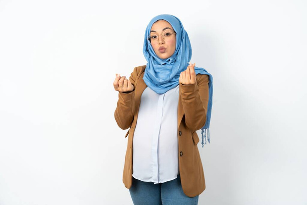 musulmana embarazada vistiendo hijab haciendo gesto de dinero con las manos, pidiendo pago de sueldo, negocio millonario - Foto, Imagen