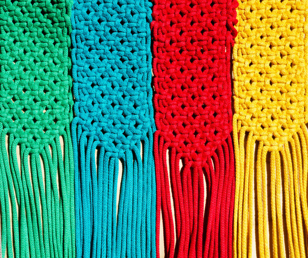 Técnica de macramé, un nudo cuadrado de hilos multicolores. Rayas de macramé de colores en colores azul, amarillo, rojo, beige, verde y rosa. - Foto, imagen